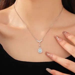 Elegant blue teardrop necklace with zircon-set fish tail pendant on a silver chain.