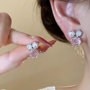 Detail of elegant pink zircon flower and pearl stud earrings with silver needles