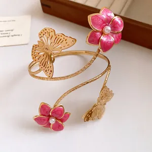 Close-up of vintage gold arm cuff with pink enamel flowers and delicate butterfly detail