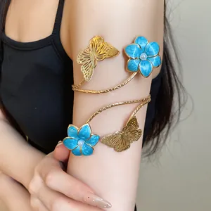 Close-up of a vintage gold-toned arm cuff featuring blue enamel flowers and metal butterflies