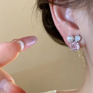 Close-up shot of elegant pink zircon flower and pearl cluster stud earrings on ear