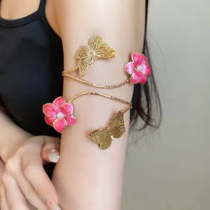 Detailed view of an elegant golden arm cuff featuring pink enameled flowers and butterflies