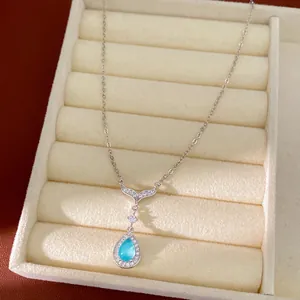 Close-up detail of blue teardrop stone pendant and zircon-inlaid fish tail necklace