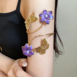 Close-up of elegant gold arm cuff with purple enamel flowers and butterfly charms