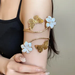 Close-up detail of a vintage gold arm cuff featuring white flowers and butterfly charms