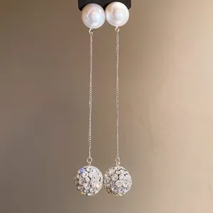 Close-up of elegant long silver earrings with white pearls and sparkling rhinestone balls