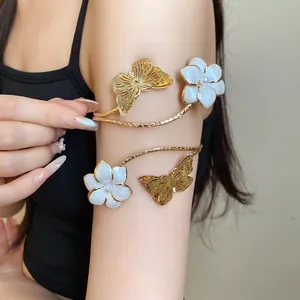 Detailed view of an elegant gold butterfly and enamel flower arm cuff worn on a model's arm.