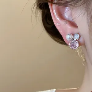 Macro view of an elegant pink crystal and pearl stud earring worn on a model's ear