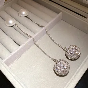 Elegant silver drop earrings featuring pearls and crystal-encrusted spheres in a jewelry box.