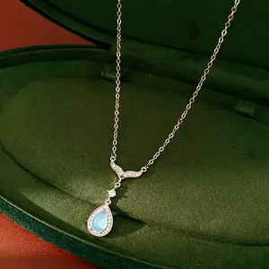 Close-up detail of silver necklace featuring zircon fishtail and blue teardrop pendant