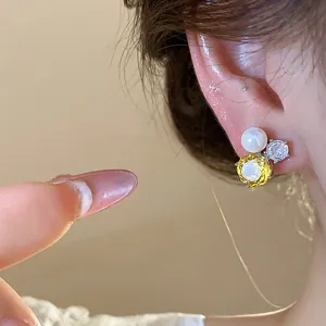 Close-up of elegant yellow zircon and pearl stud earrings worn on the ear model