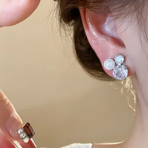 Close-up detail of elegant silver needle zircon flower and pearl stud earrings for women