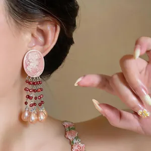 Close-up detail of vintage pink cameo earrings with red bead tassels and pink pearls