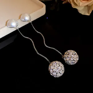 Close-up of elegant silver drop earrings with pearls and shimmering pave diamond balls.