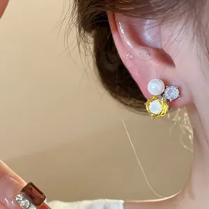 Close-up of elegant zircon and pearl flower stud earring worn on ear for detail view
