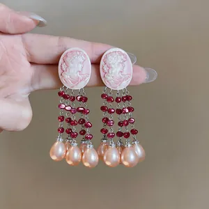Close-up detail of vintage pink cameo earrings featuring elegant tassel pearls.