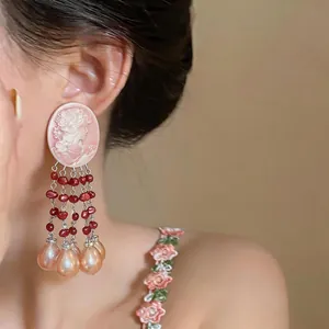 Close-up detail of vintage pink cameo tassel earrings with red beads and teardrop pearls