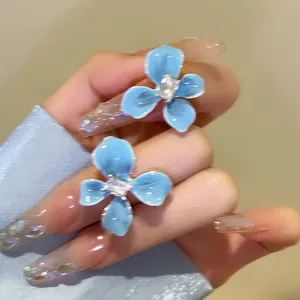 Macro detail shot of elegant sea salt blue flower stud earrings with a central sparkling crystal