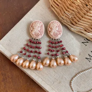 Detail view of vintage cameo earrings with red beads and peach pearl tassels
