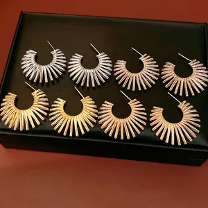 Close-up detail of stylish metallic C-shaped starburst hoop earrings in silver and gold