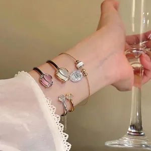 Elegant cat's eye tulip open bangle and zircon rings displayed on a model's wrist