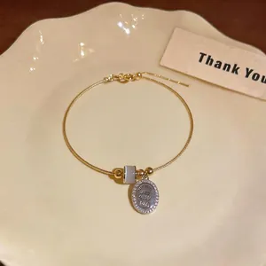 Elegant gold-tone bracelet featuring a cat's eye stone bead and zircon-encrusted charm