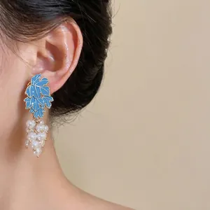 Elegant blue enamel leaf and white pearl grape cluster dangle earrings shown on model