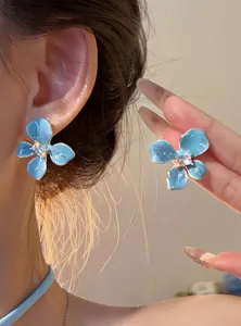 Close-up detail of sea salt blue flower stud earrings with center crystal on model ear