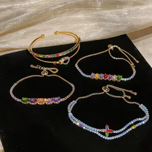 Macro detail of luxury multi-colored zircon flower and snake-shaped gold bangle bracelets