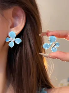 Close-up of elegant sea salt blue flower stud earrings with sparkling crystal center.