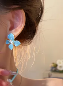 Close-up of sea salt blue flower stud earring with sparkling crystal worn on ear