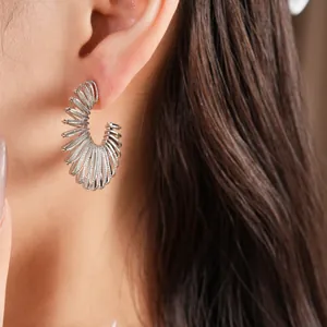 Close-up detail showing a textured silver C-shaped spiral hoop earring on a model ear