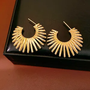 Detailed view of gold-colored sunburst C-shaped earrings with textured finish