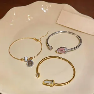 Detail view of gold and silver tulip cuff bracelets with cat-eye stones and zircons