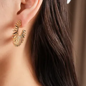 Close-up of elegant gold C-shaped spiral hoop earrings for women shown on model ear