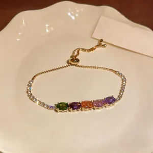 Detail of gold adjustable bracelet featuring multi-colored oval cubic zirconia stones