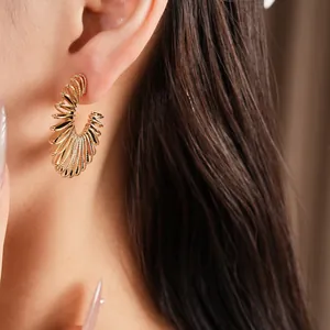 Macro detail of elegant golden spiral C-shaped hoop earring showing textured finish