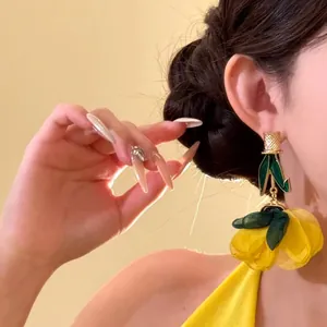 Détails des boucles d'oreilles fleurs jaunes surdimensionnées portées par le modèle