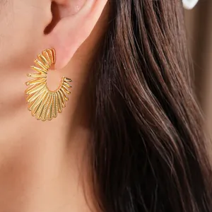 Close-up view of elegant gold C-shaped ribbed hoop earrings worn on a female model's ear