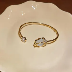 Detailed shot of an elegant gold tulip bangle featuring cat's eye stone and zirconia crystals