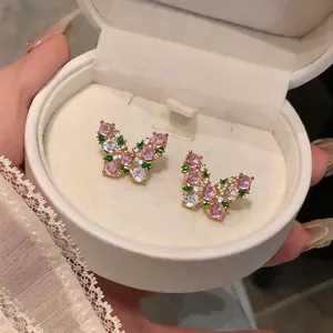 Close-up of butterfly stud earrings with pink and green zircons in a jewelry box