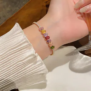 Close-up of a gold-plated bracelet featuring vibrant oval-shaped multi-colored stones