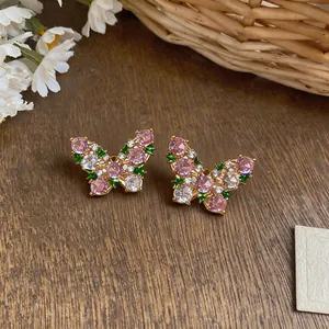 Detailed macro view of elegant gold butterfly stud earrings featuring pink and clear zircons