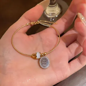 Elegant close-up of a gold wire bracelet with cat eye stone and zircon pendant on female hand