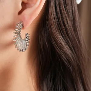Detail view of stylish silver-tone C-shaped spiral hoop earrings on a female model
