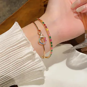 Detailed view of elegant gold-toned bangles with colorful zircons and heart charms