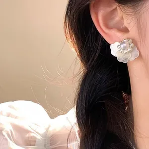 Elegante Blumenblatt-Ohrstecker mit Perlen, getragen von einem Modell in weichem Licht