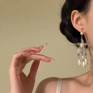 Elegant silver starfish tassel earrings with pearls shown on a female model's ear