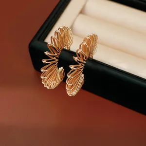Detailed macro view of gold plated spiral wire C-shape hoop earrings in a jewelry box