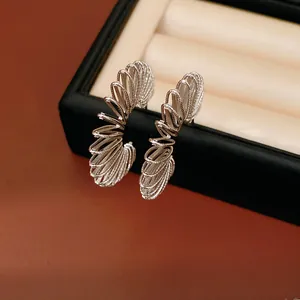 Detail view of elegant silver-toned spiral C-shaped hoop earrings on a black box
